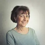 Smiling middle-aged woman wearing a gray sweater against a neutral background