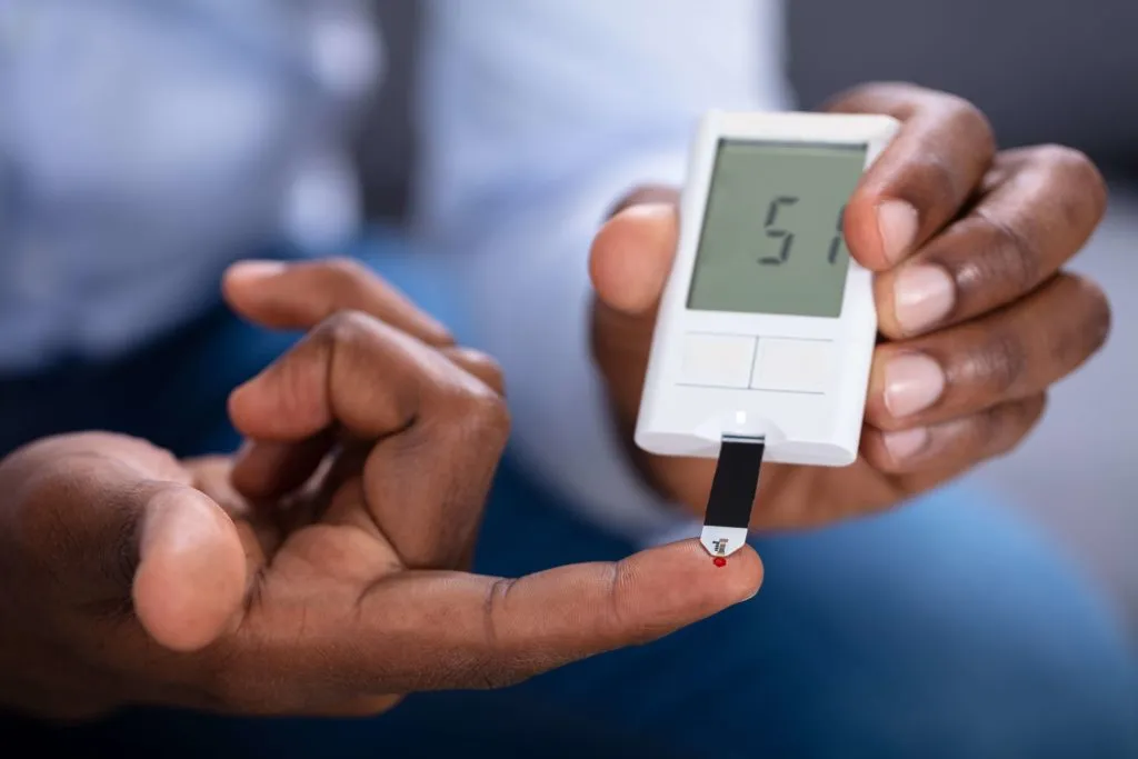 Person checking blood glucose level with digital diabetes monitor