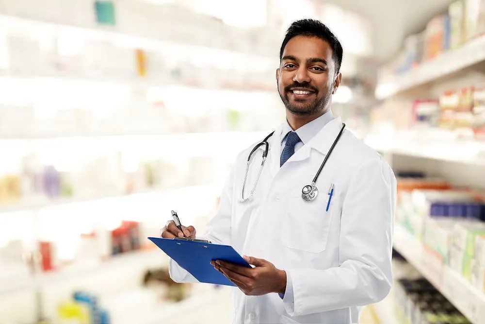 Pharmacist in pharmacy holding clipboard and smiling