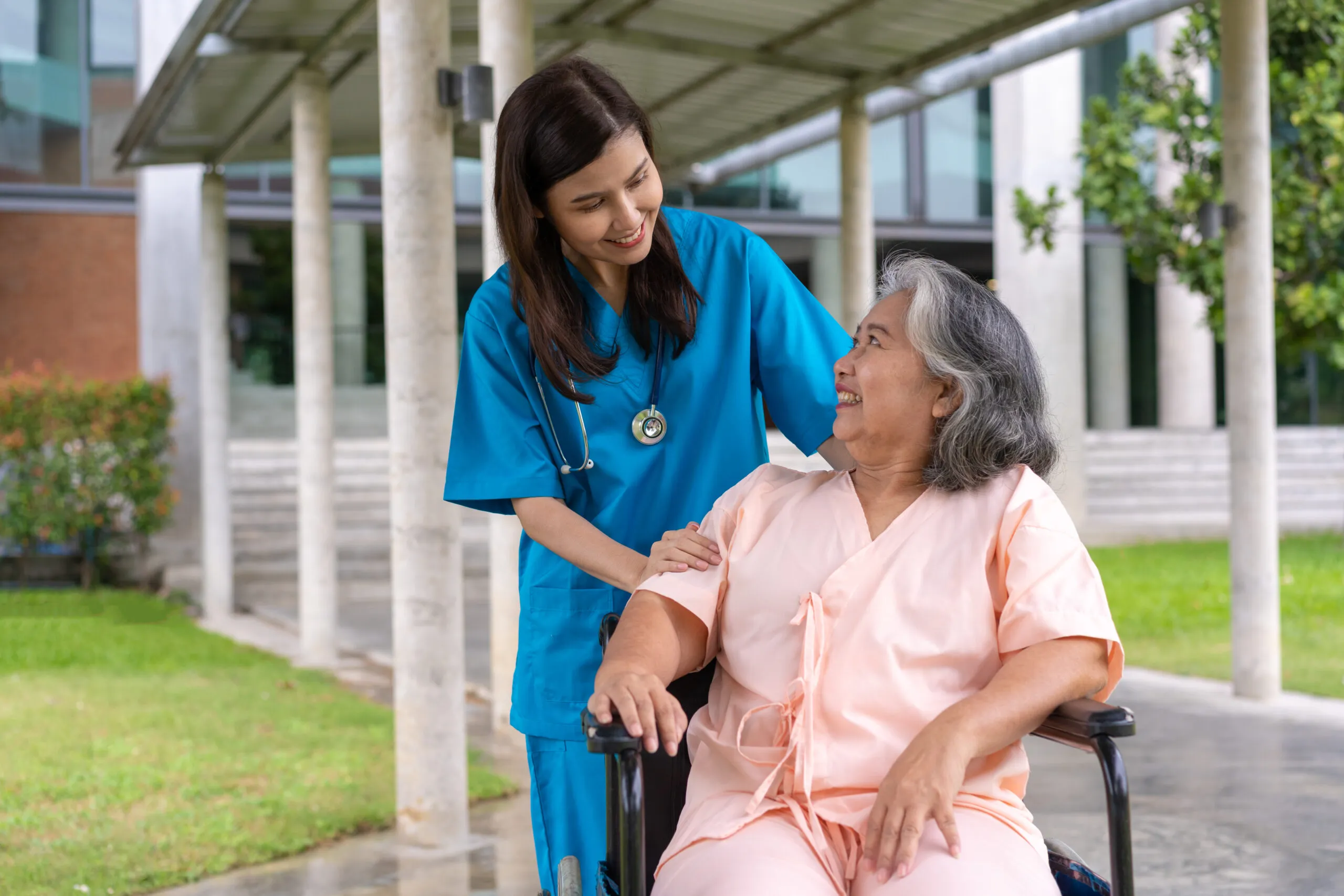 Caregiver assisting elderly woman in wheelchair during transitional care support