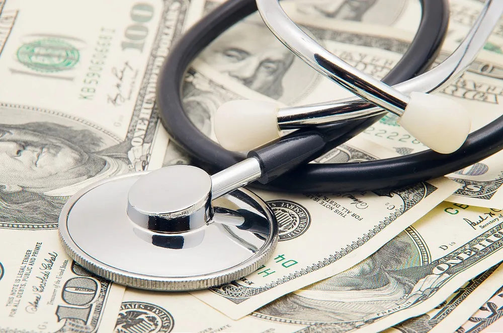 Healthcare costs and medical expenses concept with stethoscope on dollar bills