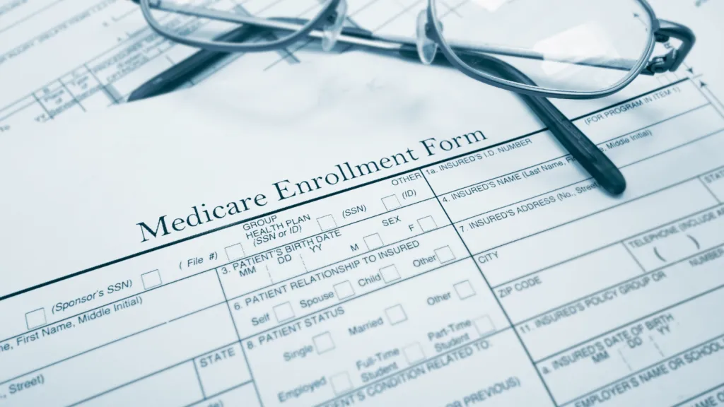 Medicare enrollment form with eyeglasses and healthcare paperwork