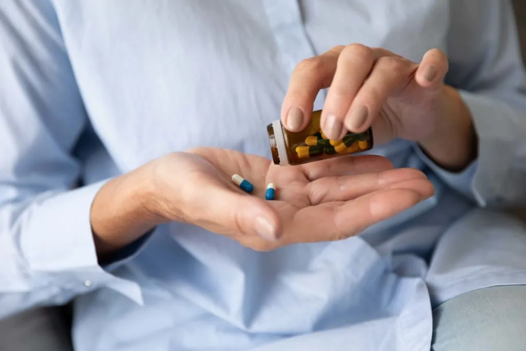 Person pouring prescription pills into hand close-up