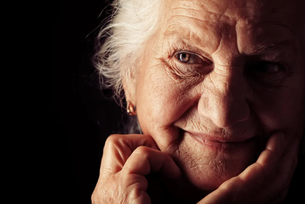 Close-up portrait of smiling elderly woman in dramatic lighting