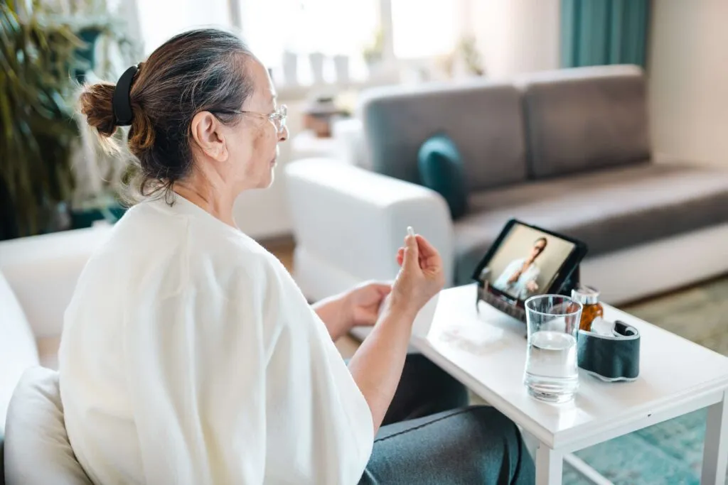 Senior woman taking medication during virtual healthcare consultation