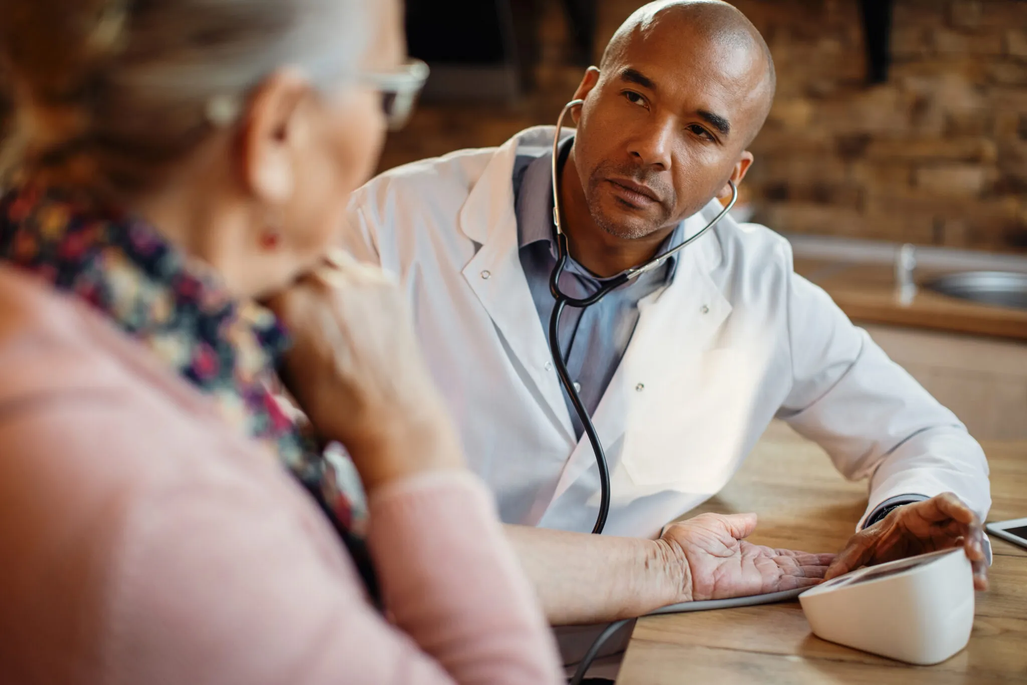 Doctor checking blood pressure of senior woman during home healthcare visit