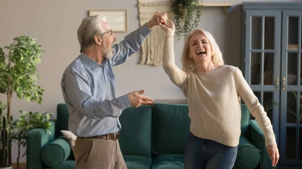 Happy senior couple dancing together at home for healthy active lifestyle