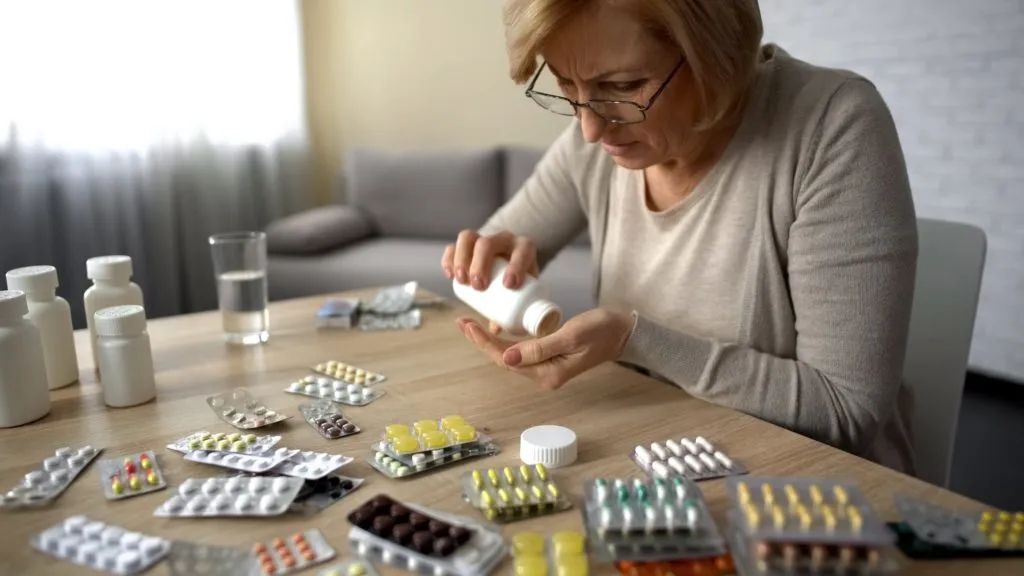Older adult organizing multiple prescription medications at home