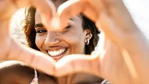 Smiling woman making heart shape with hands close-up portrait