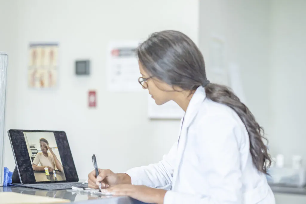 Healthcare professional conducting telehealth consultation on laptop