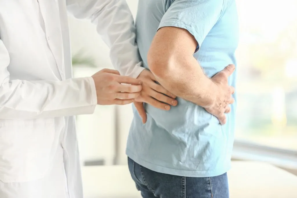 Doctor examining patient with back pain during medical consultation