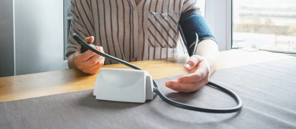 Person checking blood pressure with digital monitor at home