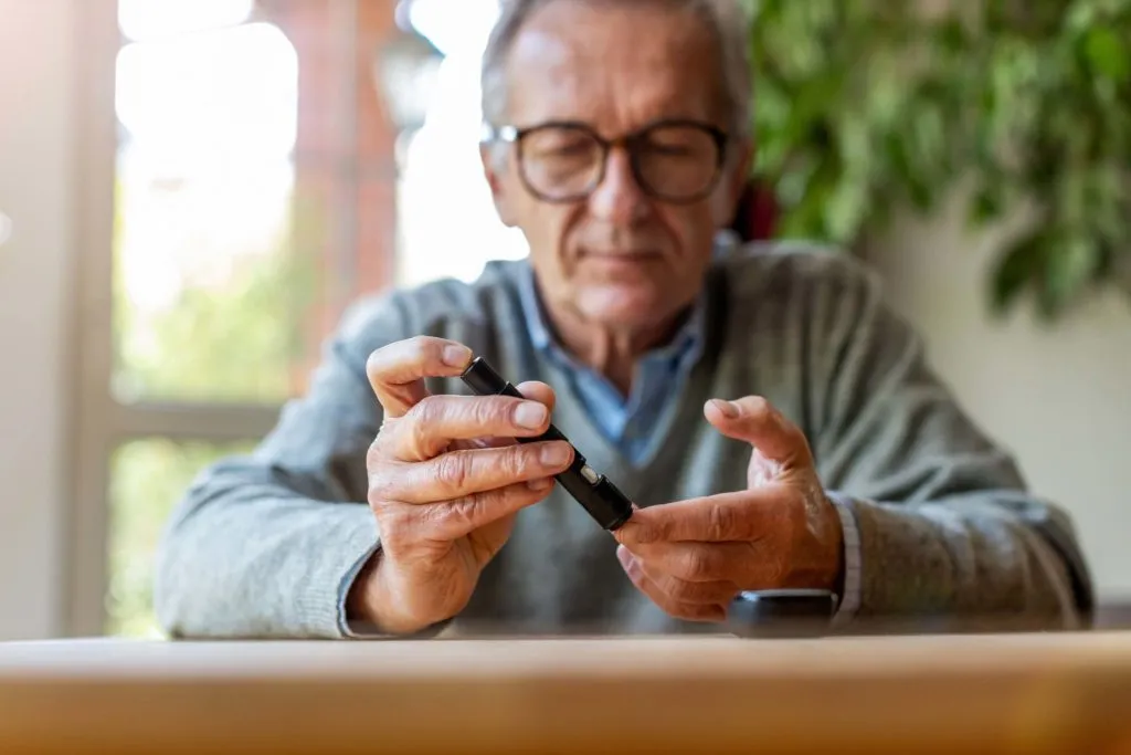 Senior man using insulin pen for diabetes treatment at home