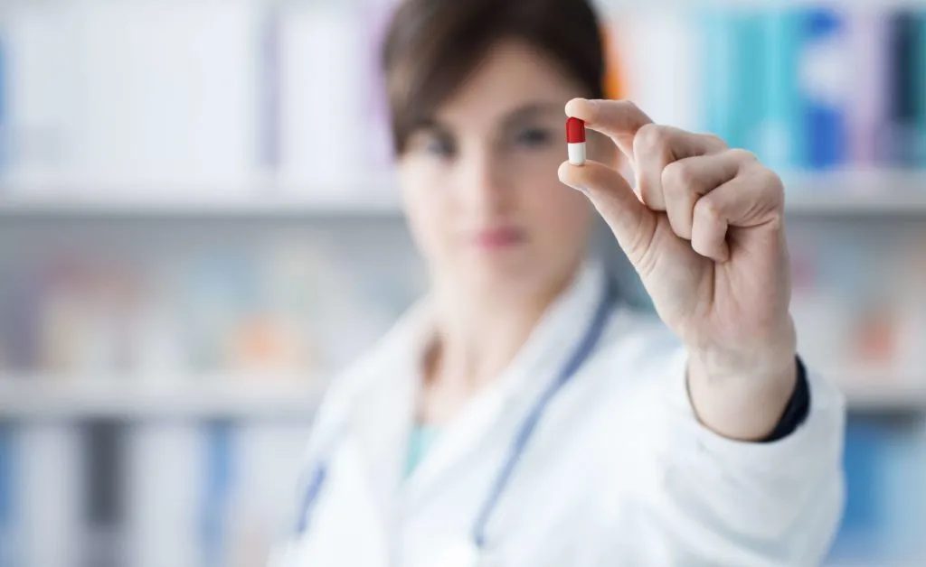 Doctor holding red and white capsule medicine close-up