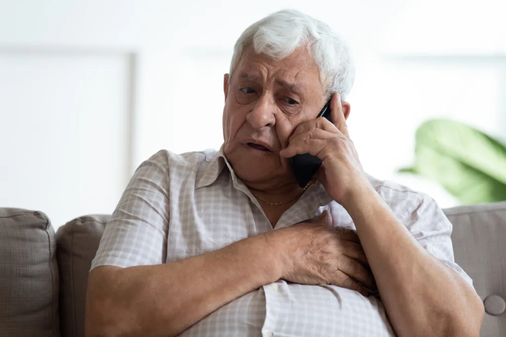 Elderly man having chest pain while talking on smartphone