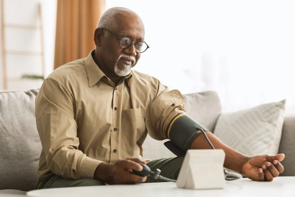 Senior man checking blood pressure at home with digital monitor