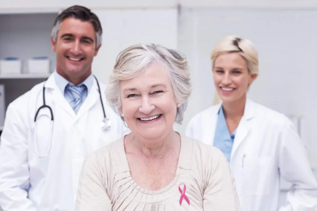 Smiling senior cancer awareness patient with healthcare team in clinic