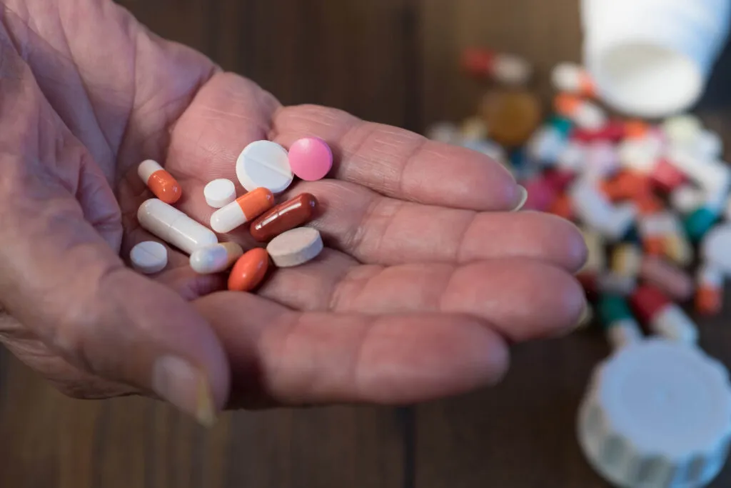 Close-up of assorted pills and capsules in elderly hand
