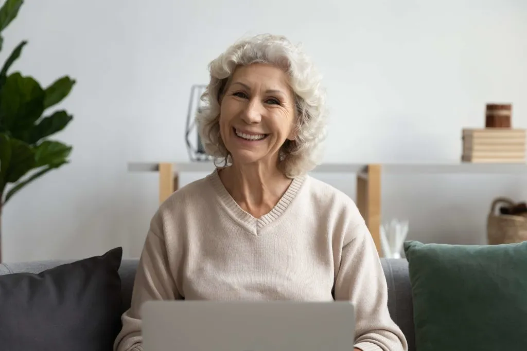 Smiling senior woman using laptop at home for online communication
